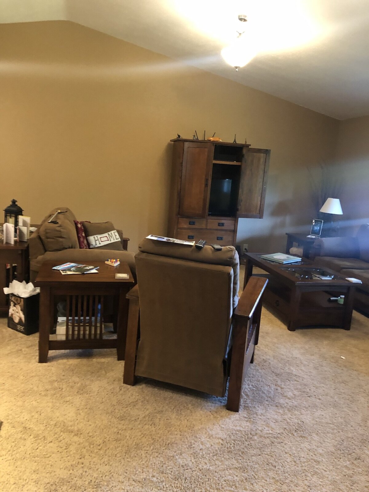 A living room with beige carpet and brown furniture