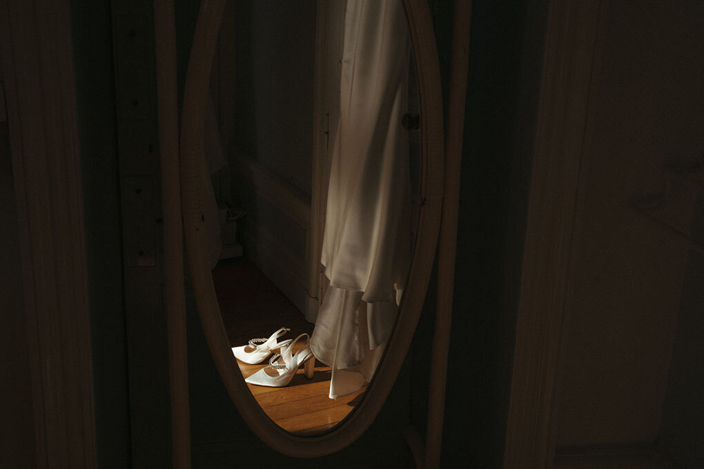 Robe de mariée suspendue se reflétant dans le miroir. Photo prise par Léa, photographe mariage vintage.
