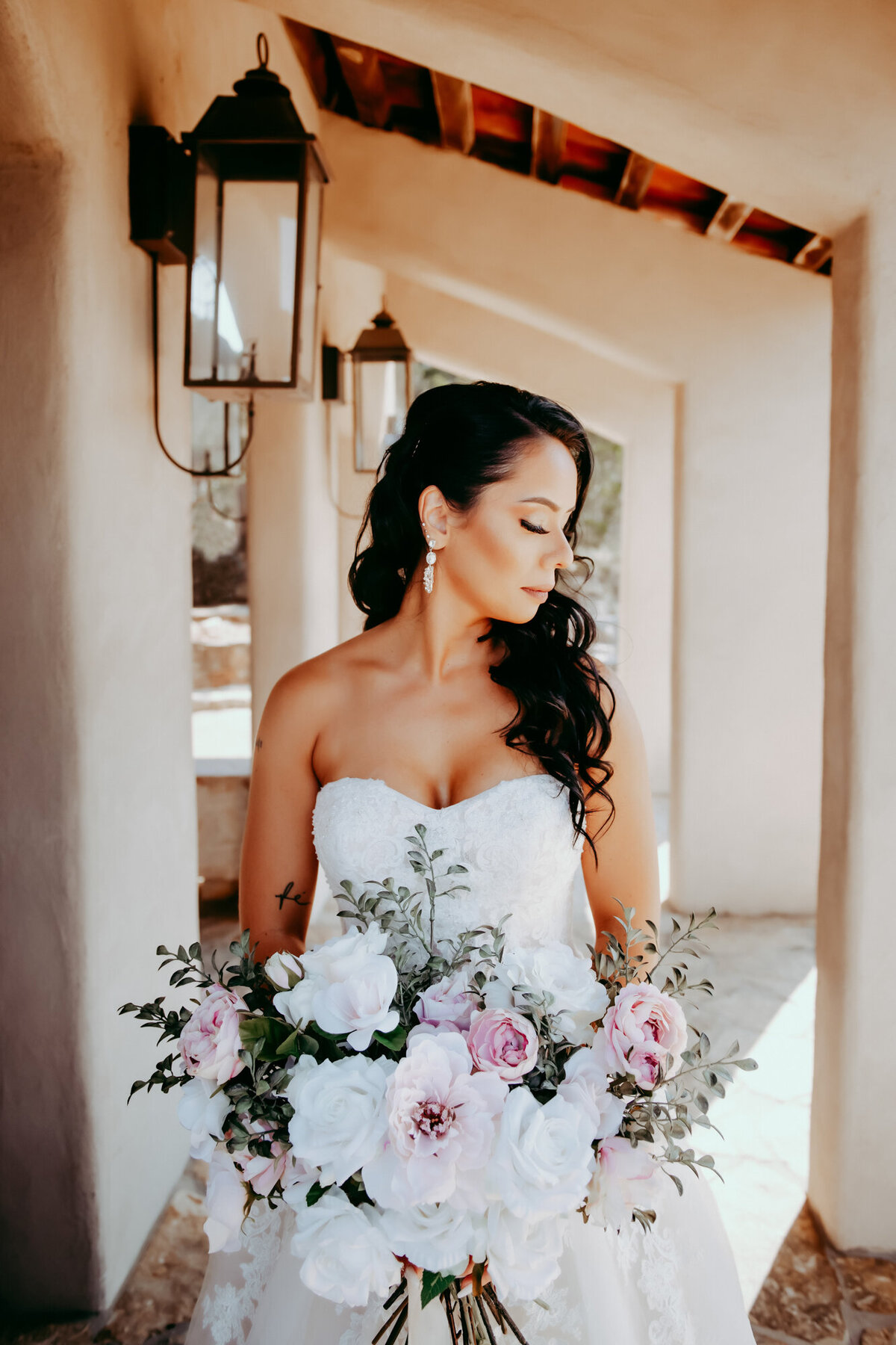 Couples Photography, a woman in wedding dress holds her bouquet as she stands outside of estate