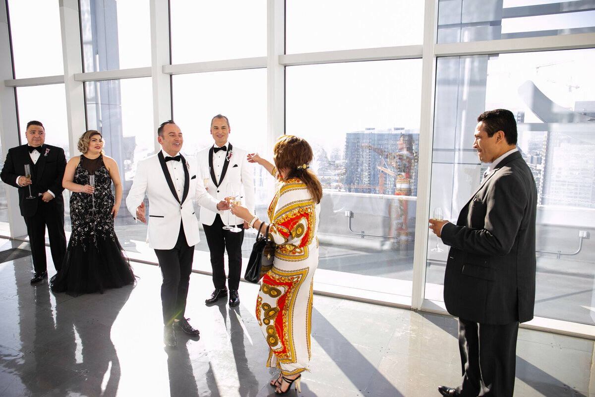 Two grooms hugging wedding guests