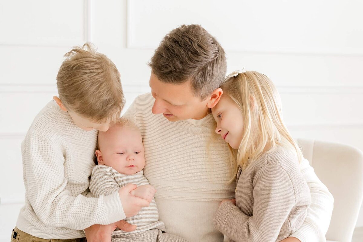 Happy family of five shares playful moments during their white studio photoshoot at Alexandra Robyn Photo + Design