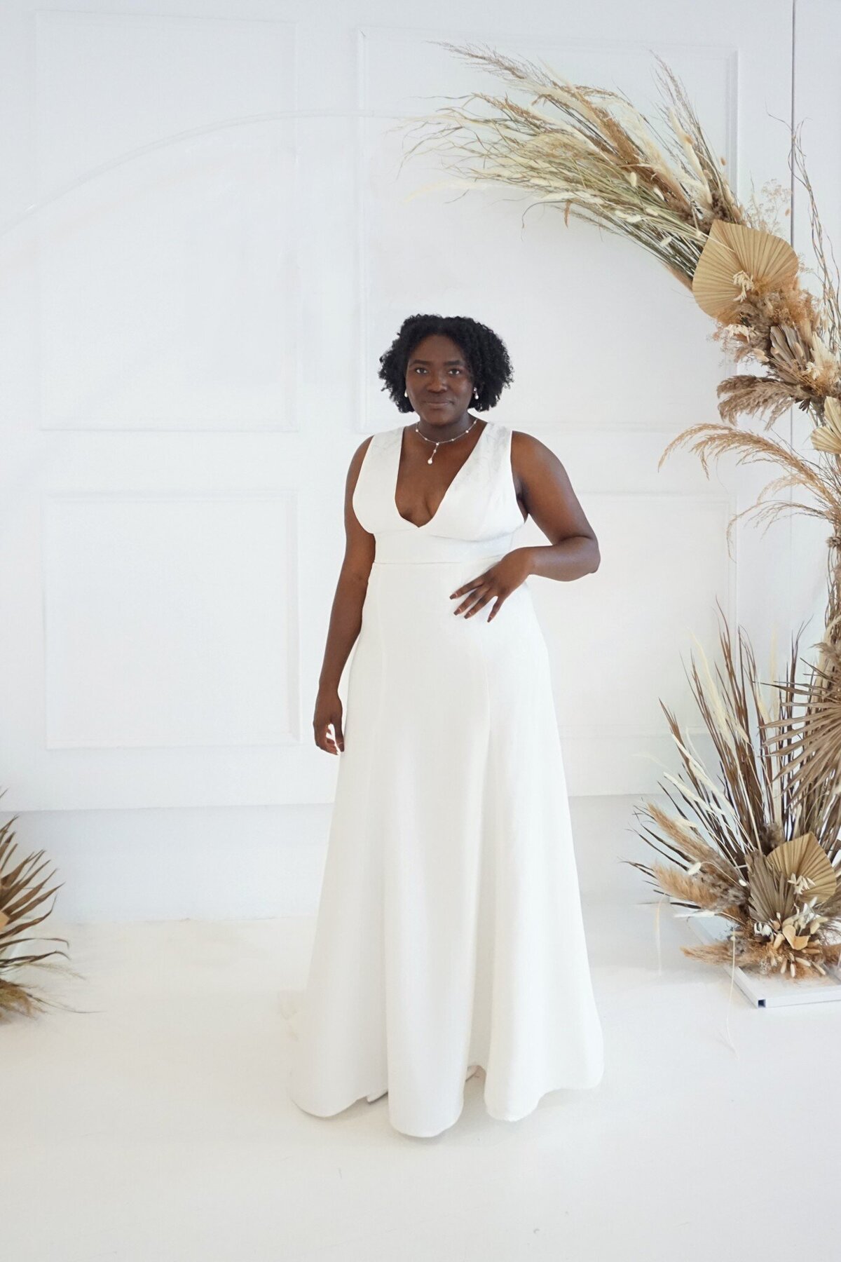 Black model in the Sol wedding dress, which features a modified a-line skirt and a v-neck bodice in a floral crepe fabric.