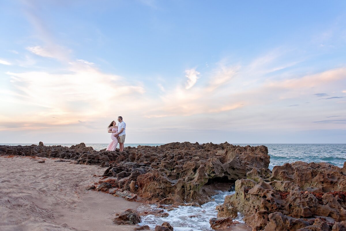 husband and wife maternity portrait on the rocks at Coral Cove beach in Jupiter