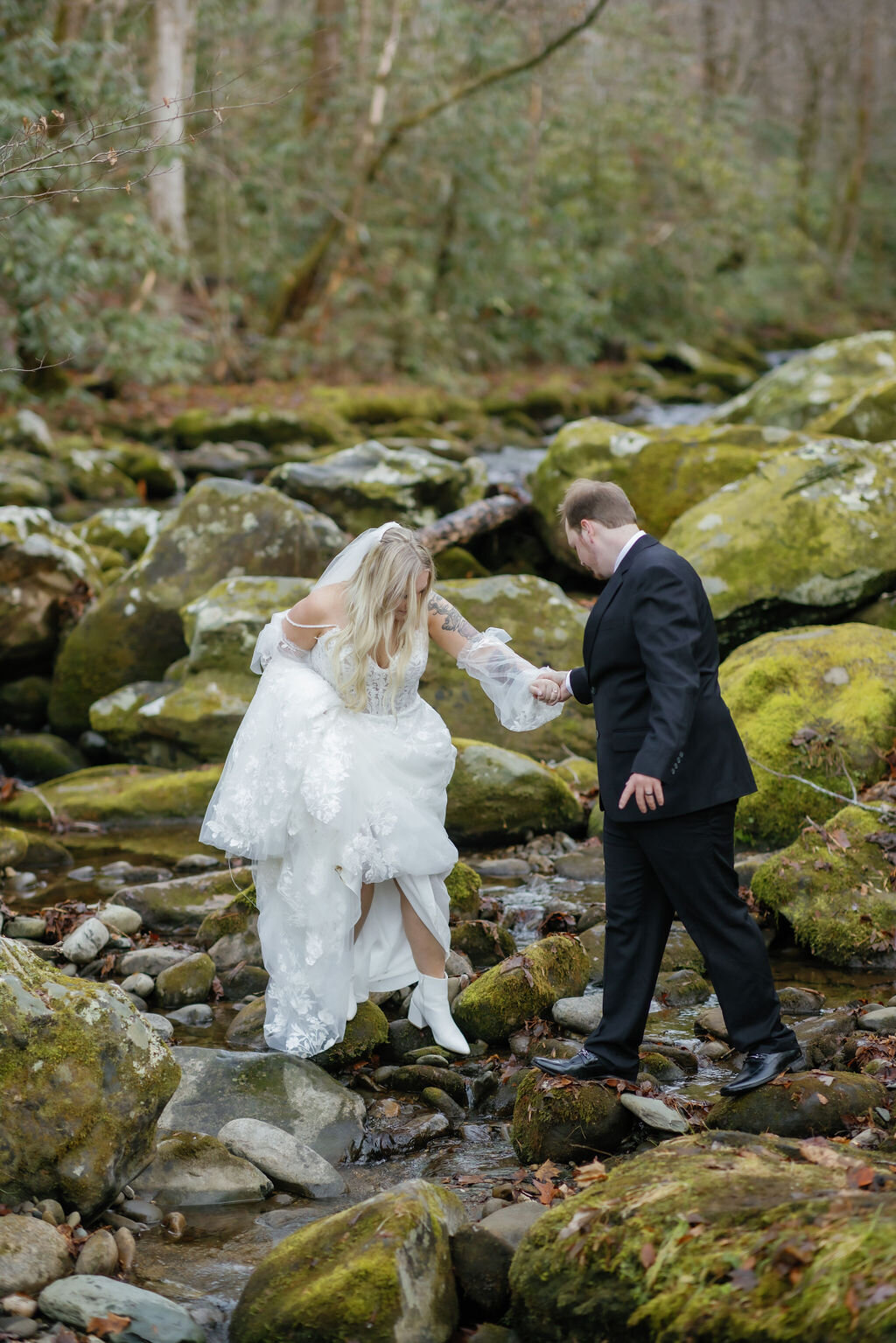 candid wedding photo by gatlinburg photographers of couple climbing through river rocks at Ely's Mill as they elope to Gatlinburg 