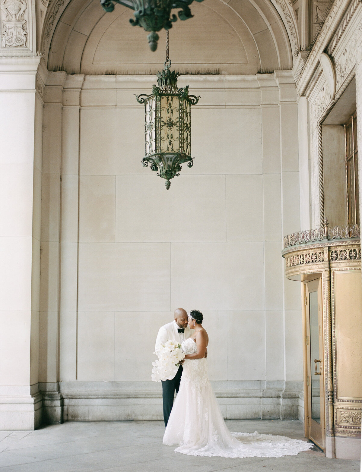 bride and groom embrace under beautiful Detroit architecture, unique Detroit wedding venue, Michigan wedding photographer