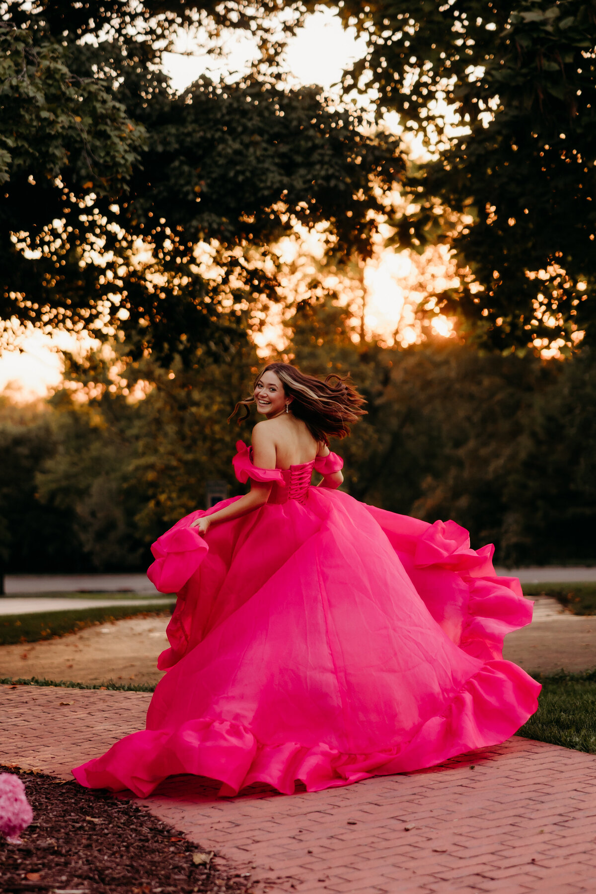 A girl in a hot pink dress runs into the sunset.
