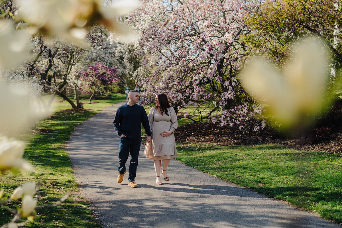 couple walking along path through trees at Finger Lakes Maternity session