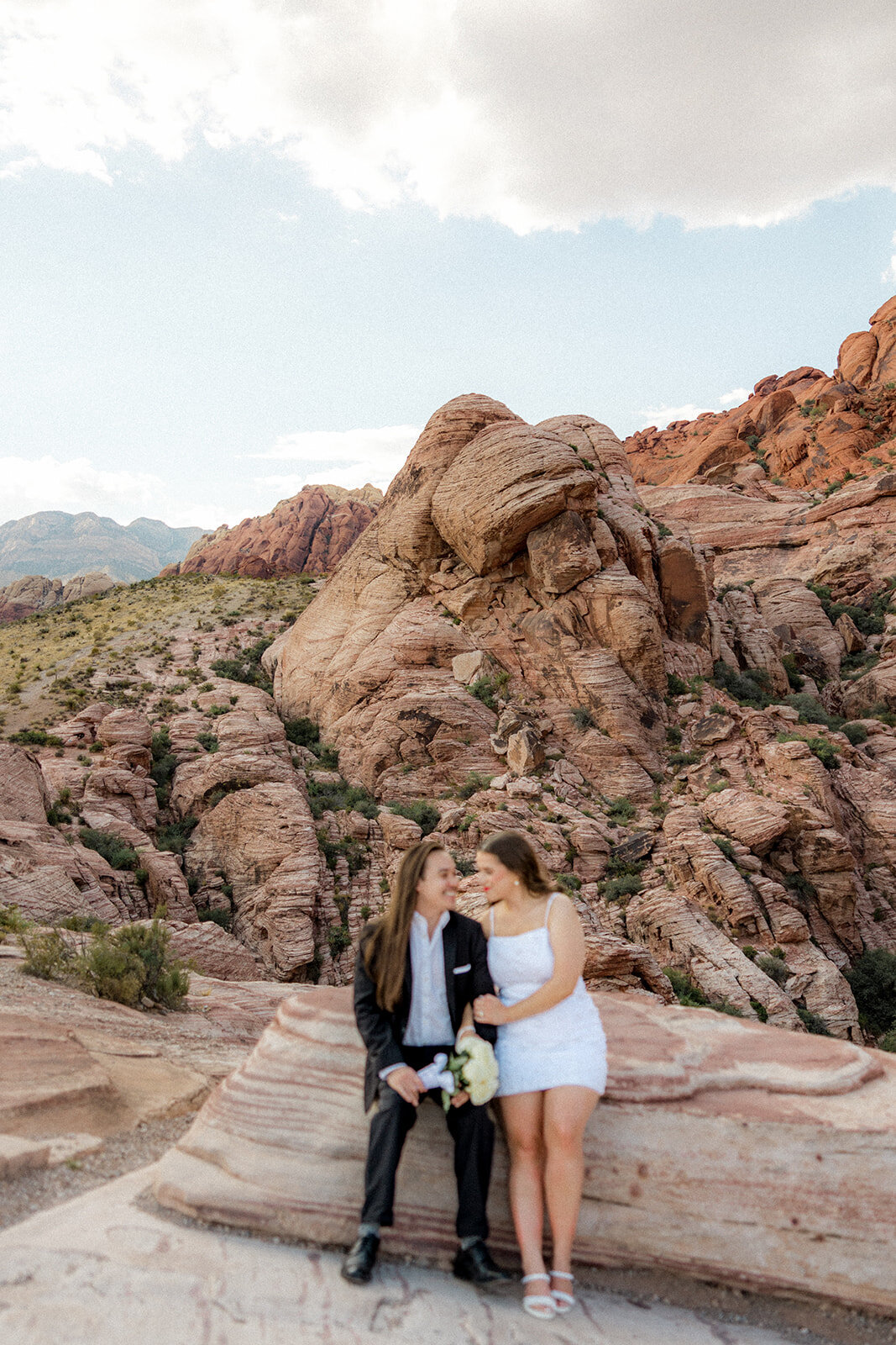 Engaged couple sitting on rock at the Red Rock Canyon smiling