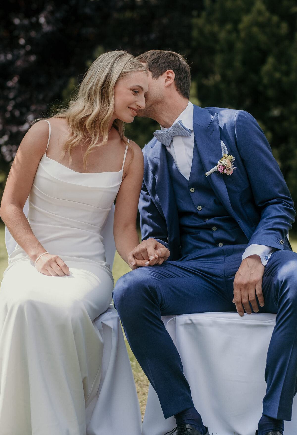 The groom whispers something sweet in the brides' ear - candid wedding photography.