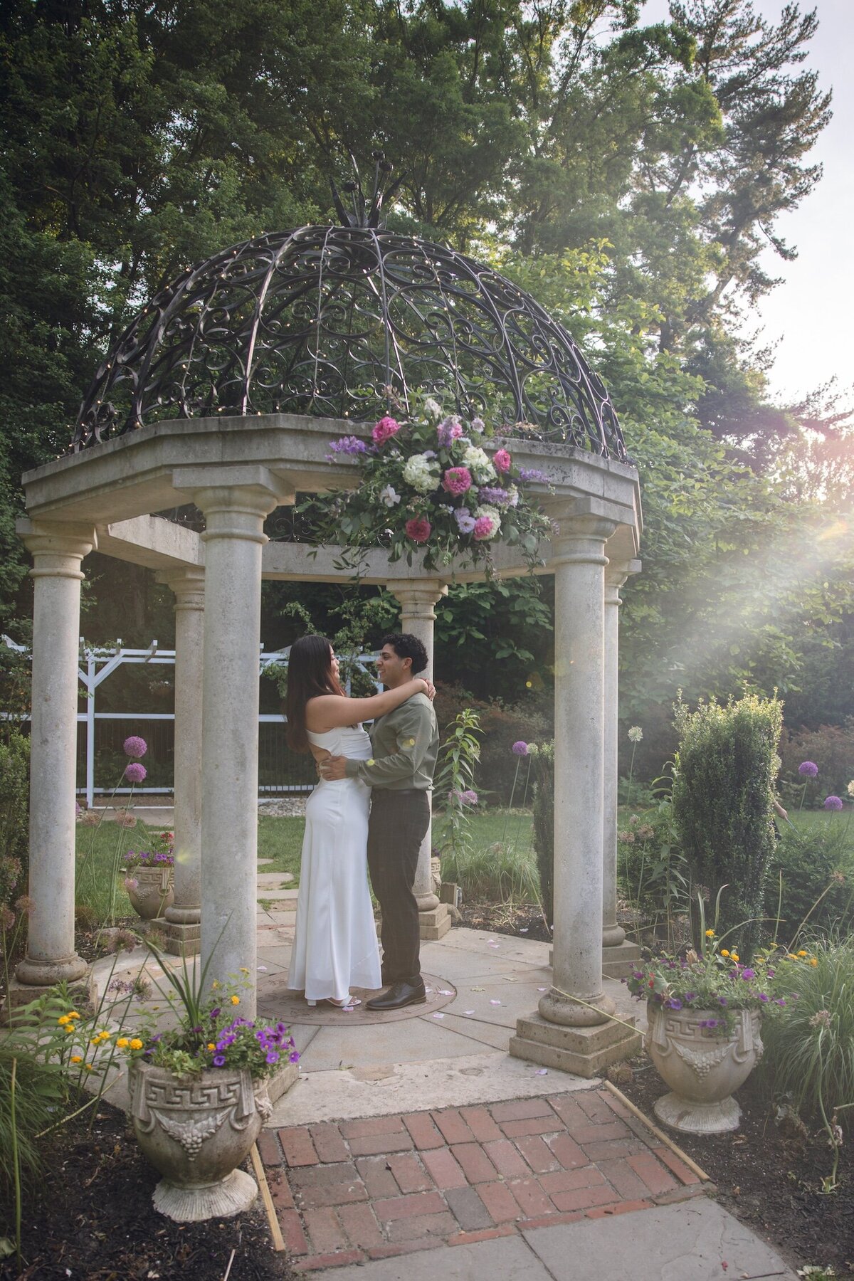 Couple walking hand-in-hand toward a stone pergola.