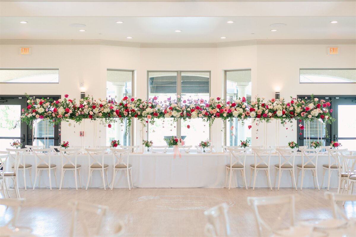 luxury head table floral centerpiece with pink daisies, roses, ranunculus, trailing greenery