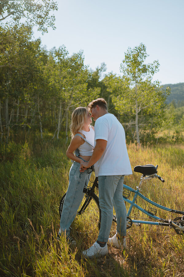 A moment captured right before a man and woman are about to kiss. Beside them is a bicycle.