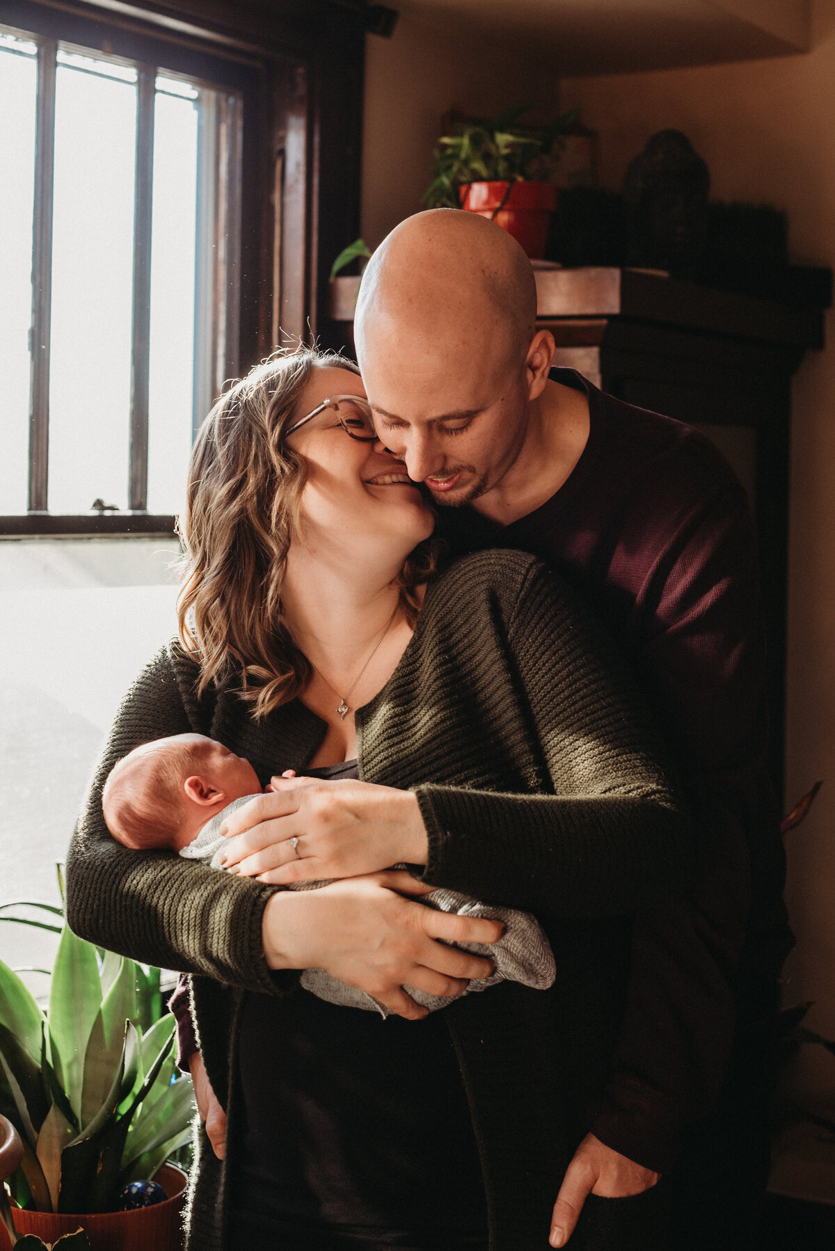 New parents share embrace with newborn in their home.