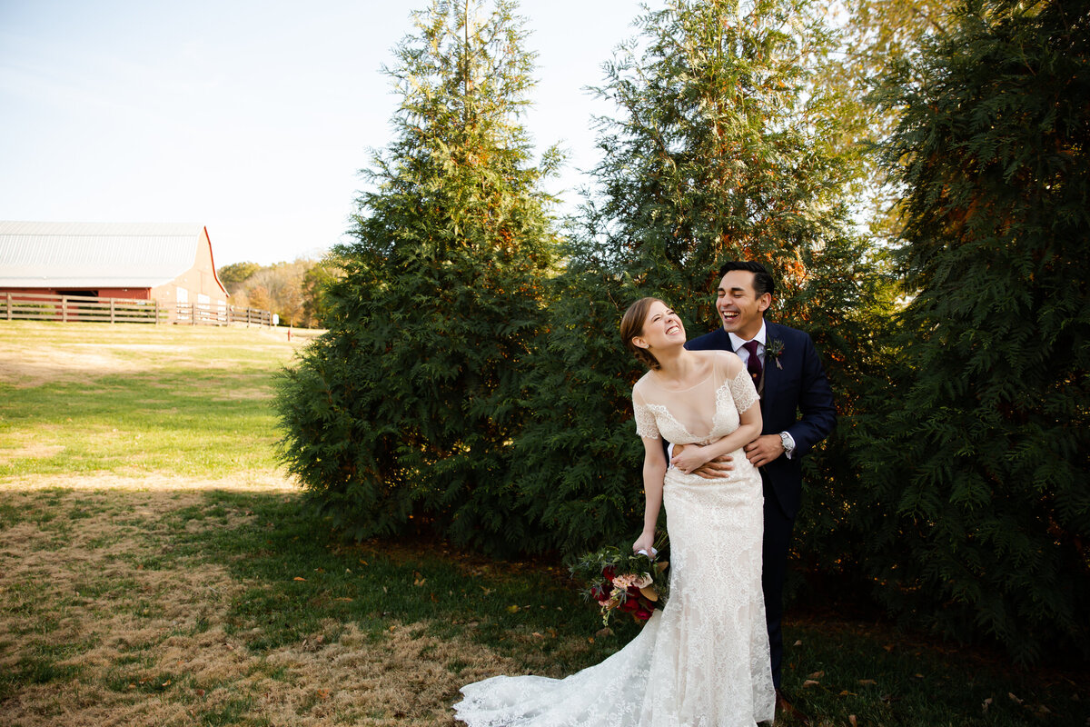 Bride in a boho lace wedding wedding gown laughing with groom in a blue suit photographed by Kansas City wedding photographer, Caia Grace