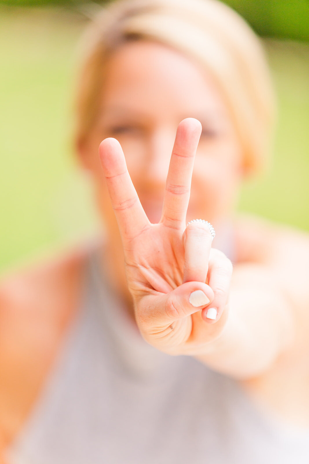 woman blurring in the background showing the peace sign with her fingers
