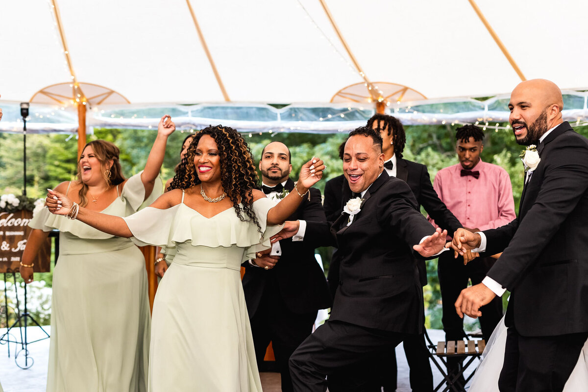 bridal party dancing in light green dresses and tux at fall wedding at The Gardens at Uncanoonuc Mountain in Goffstown NH by LIsa Smith Photogtaphy