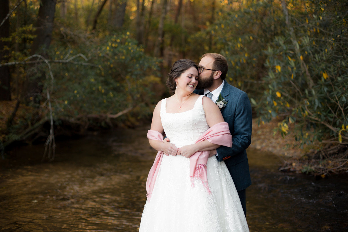 groom holds and kisses his bride while Atlanta wedding photographer captures the moment
