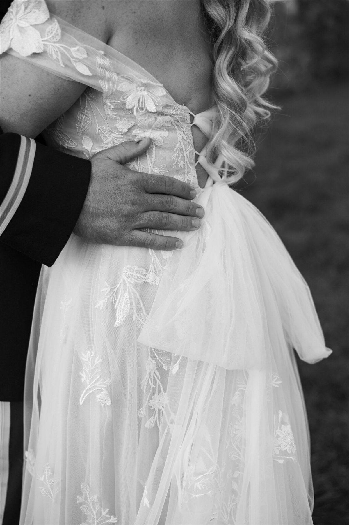 Close-up, black-and-white photo of a man in a military uniform embracing a woman in a lace wedding gown, captured by an Illinois wedding planner.