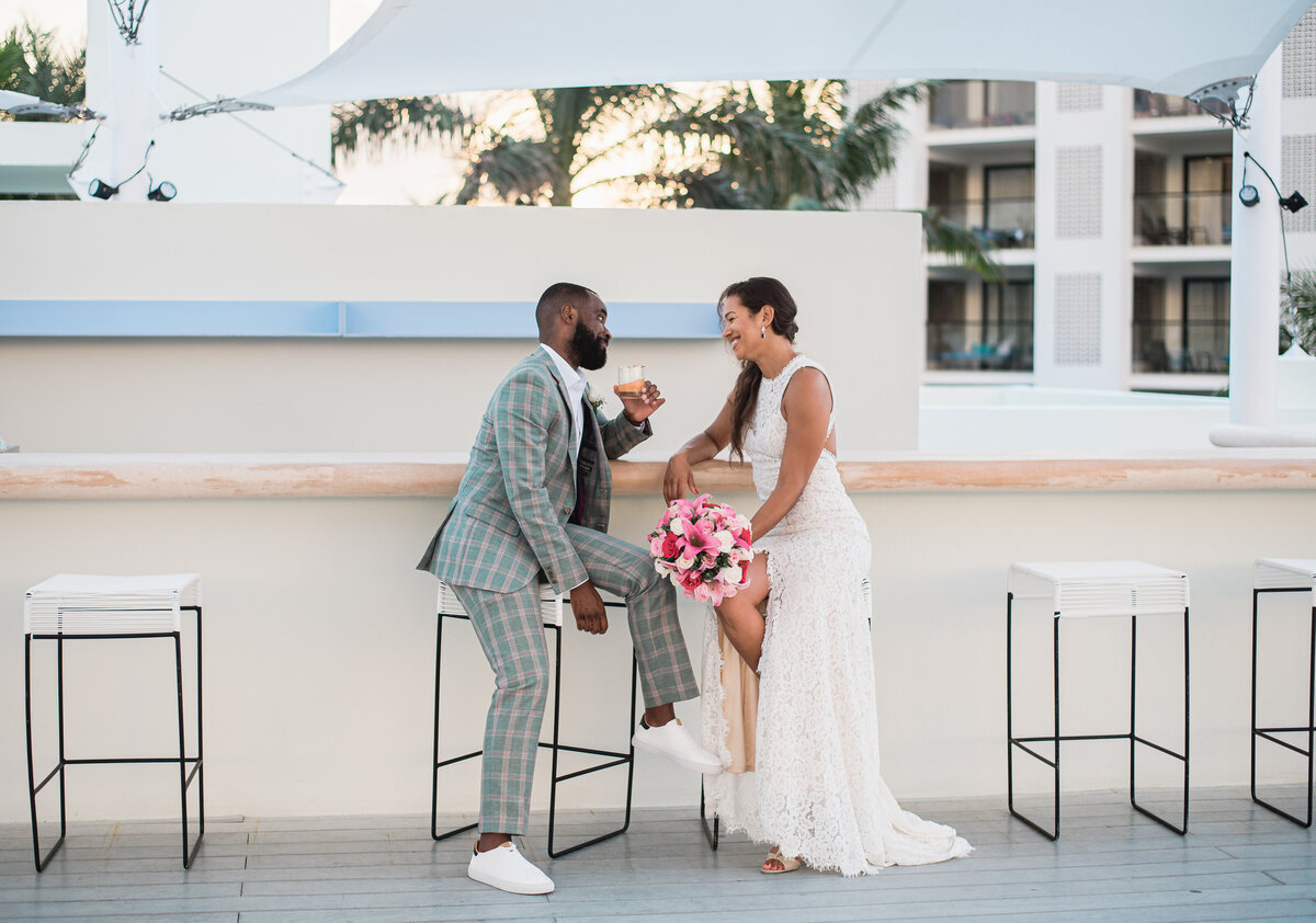 Bride and groom sit at an outdoor bar and look at each other lovingly captured by denver wedding photographer KB Radiant photography