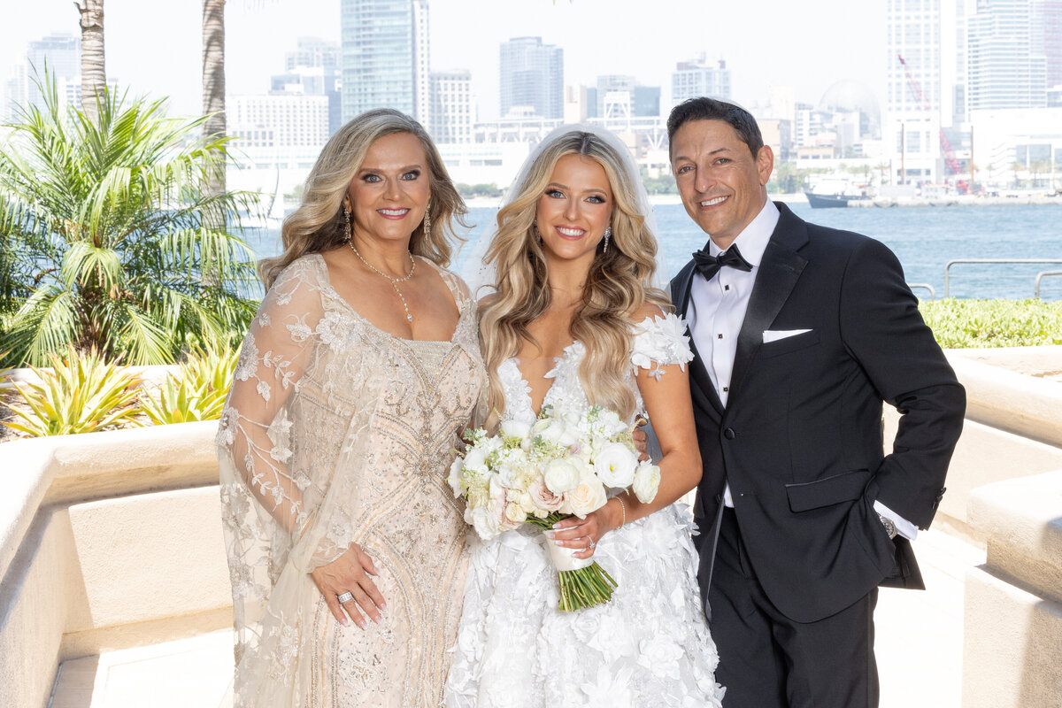 A bride smiling and standing with her parents