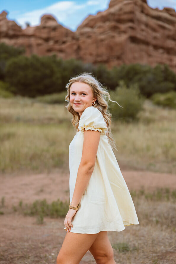 Girl in yellow dress looks at camera in a field.