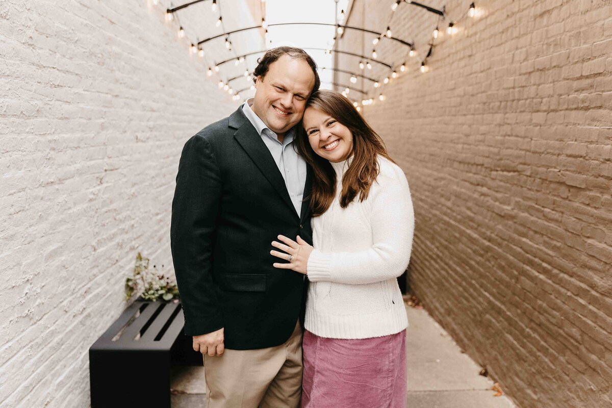 Husband and wife hold each other and smile at camera