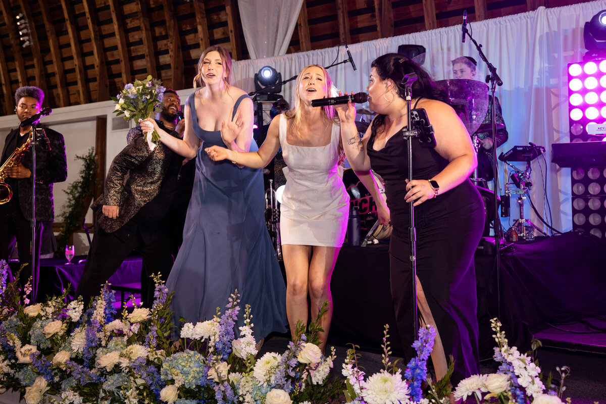 Spring wedding at WinMock at Kinderton, designed by Charming Carolina — bride and her sister, the maid of honor, singing and dancing together on stage during the reception.