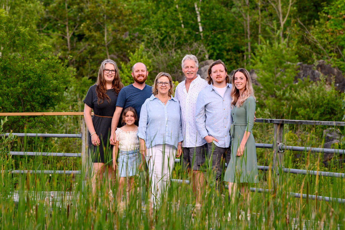 Extended family wearing blues on a bridge with greenery all around for their extended family photography session 