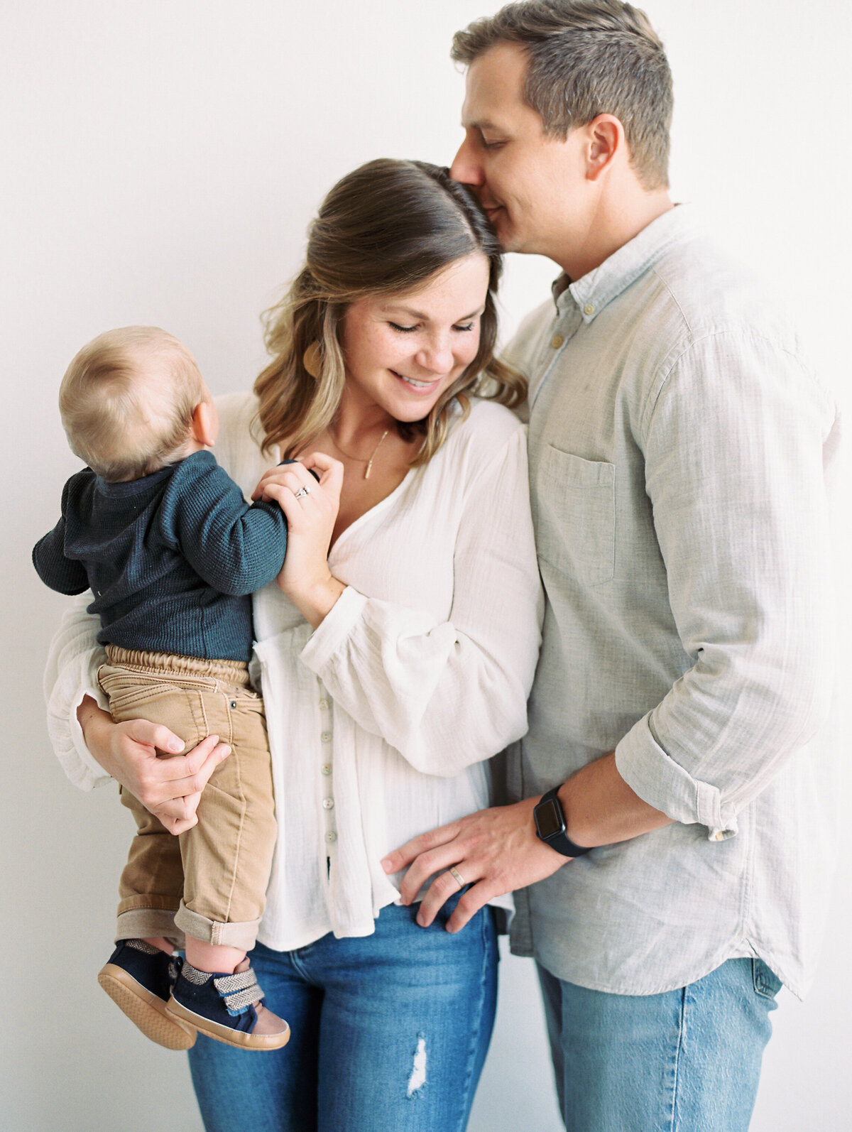 Studio portrait of a mom and dad and their baby on a white background