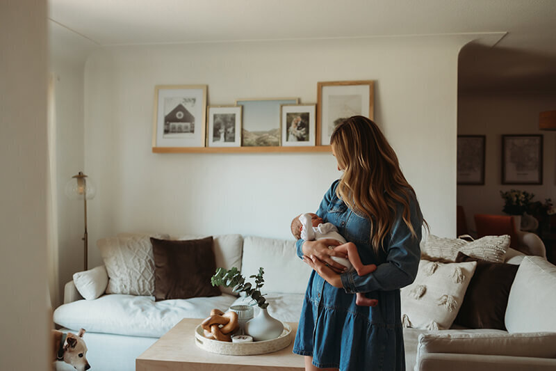 Mom sways with newborn baby boy in living room