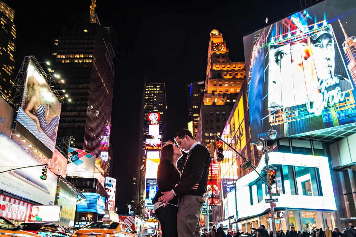 A newly engaged couple hold each other in Time Square.
