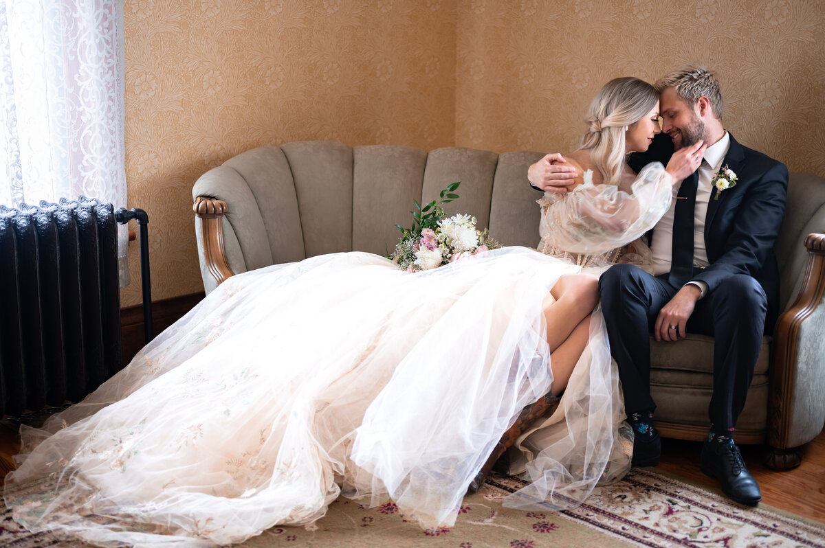 bride and groom sit on a couch and look at each other
