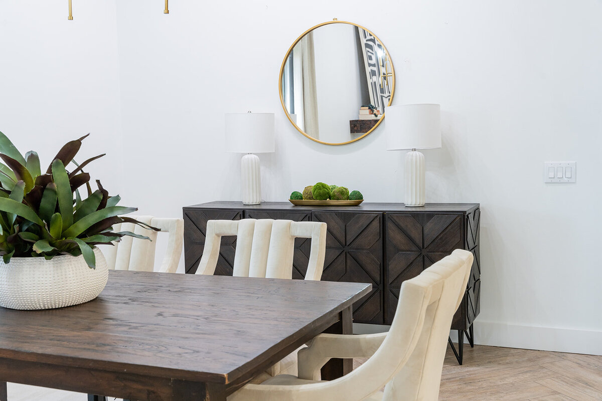 dining table with white chairs and console with lamps and mirror in background