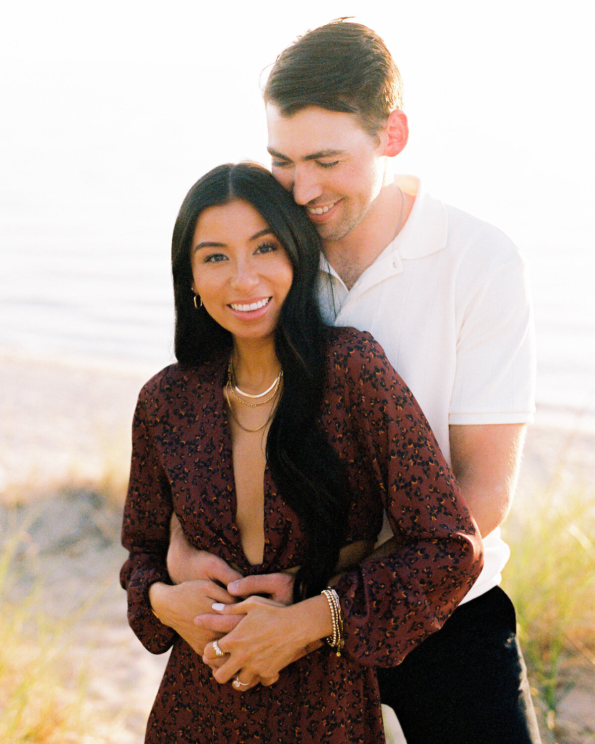 Engaged couple holding each other at oval beach in Saugatuck MI