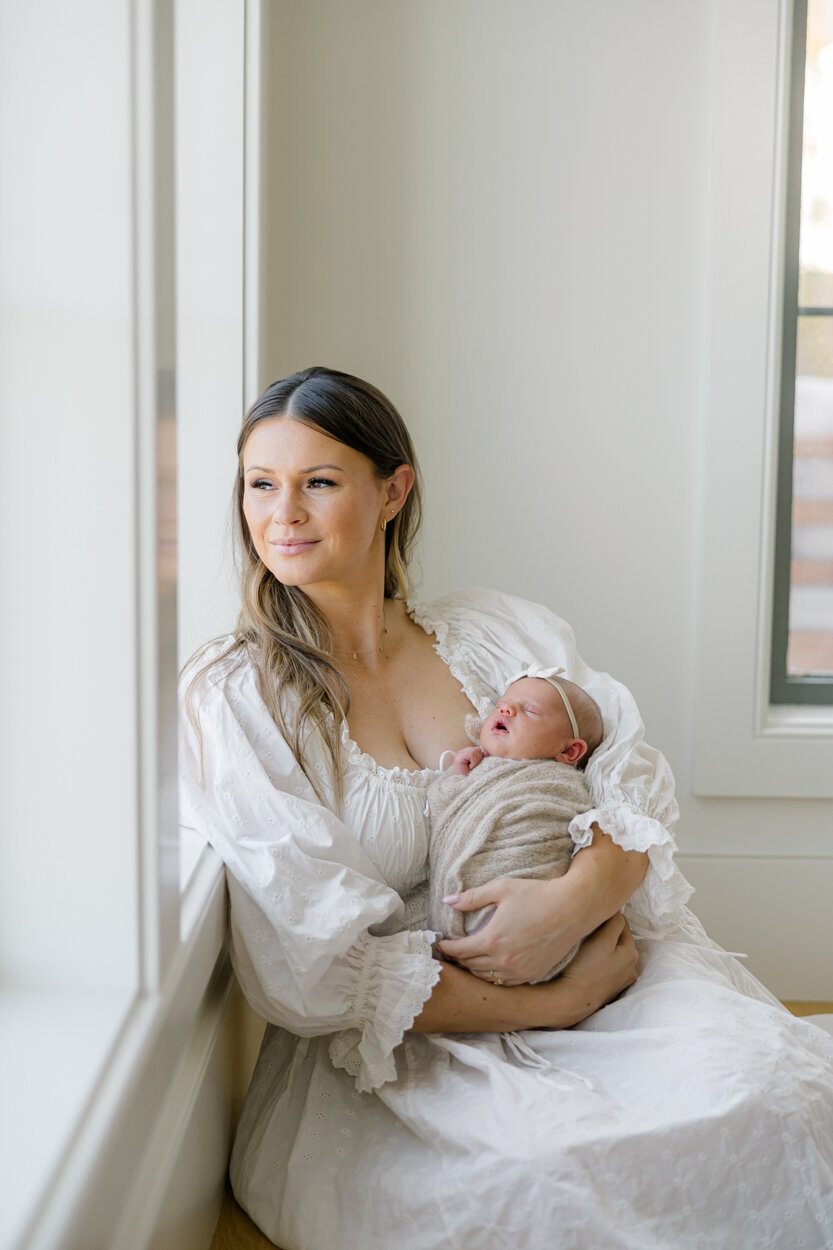 mama holding newborn by the window