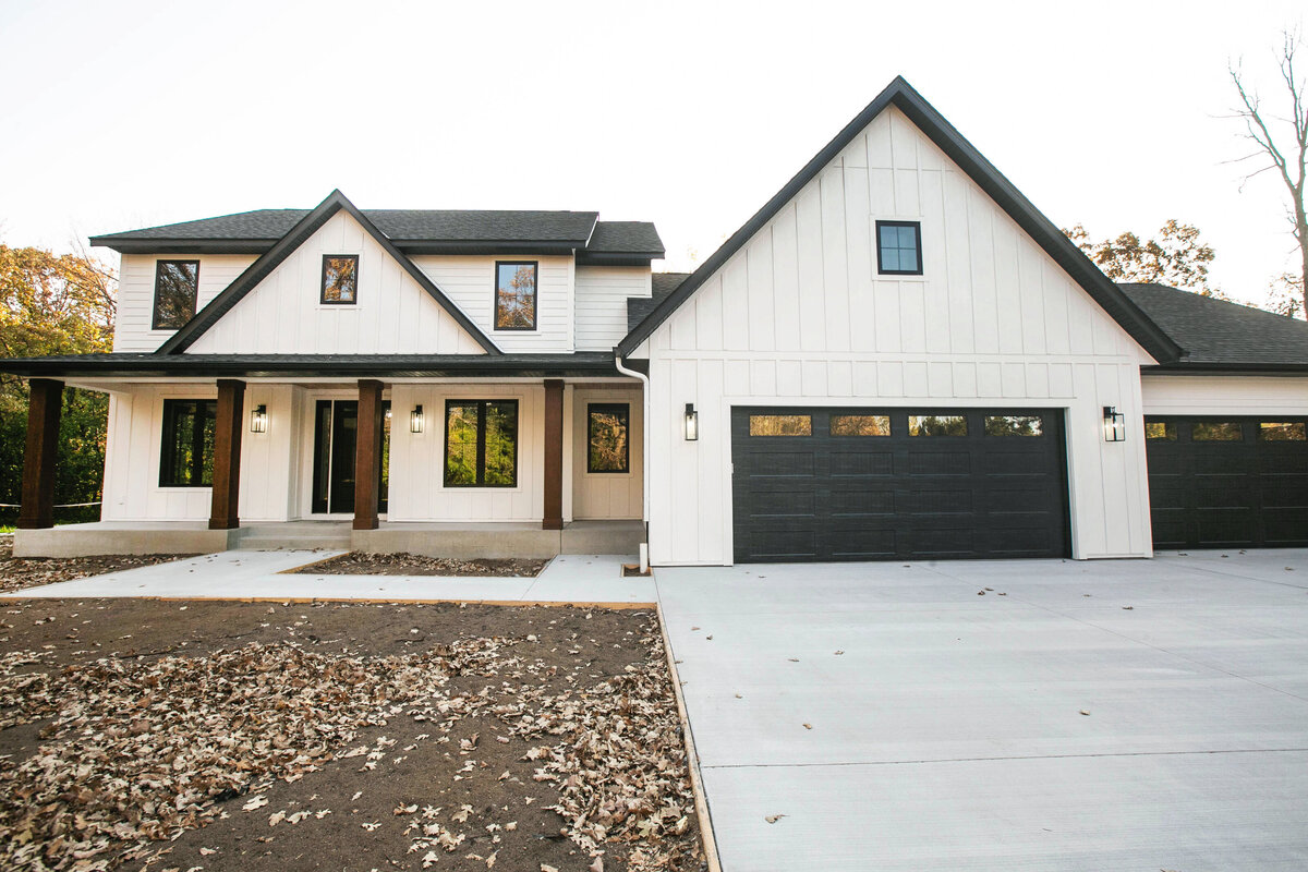 Exterior view of custom home in Big Lake Township, Minnesota with farmhouse details, cream siding, wood pillars and front porch built by Cornerstone Custom Builds
