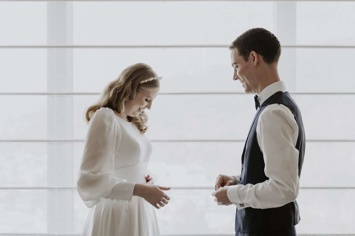 the bride wearing a white dress with long sleeves while the groom is wearing a black suit and bow tie