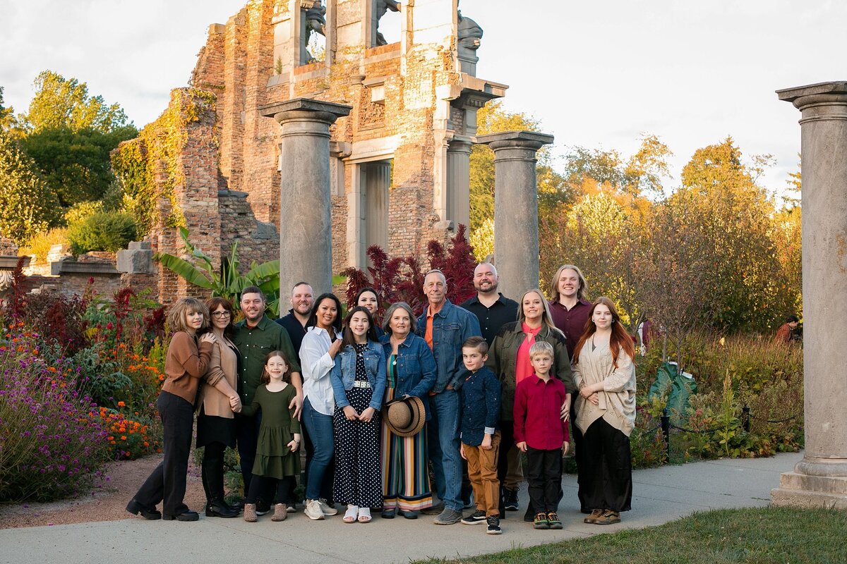 large-extended-family-smiling-together-in-front-of-historic-ruins-during-a-fall-family-session-in-indianapolis-holliday-park-meridian-kessler-meridiankessler
