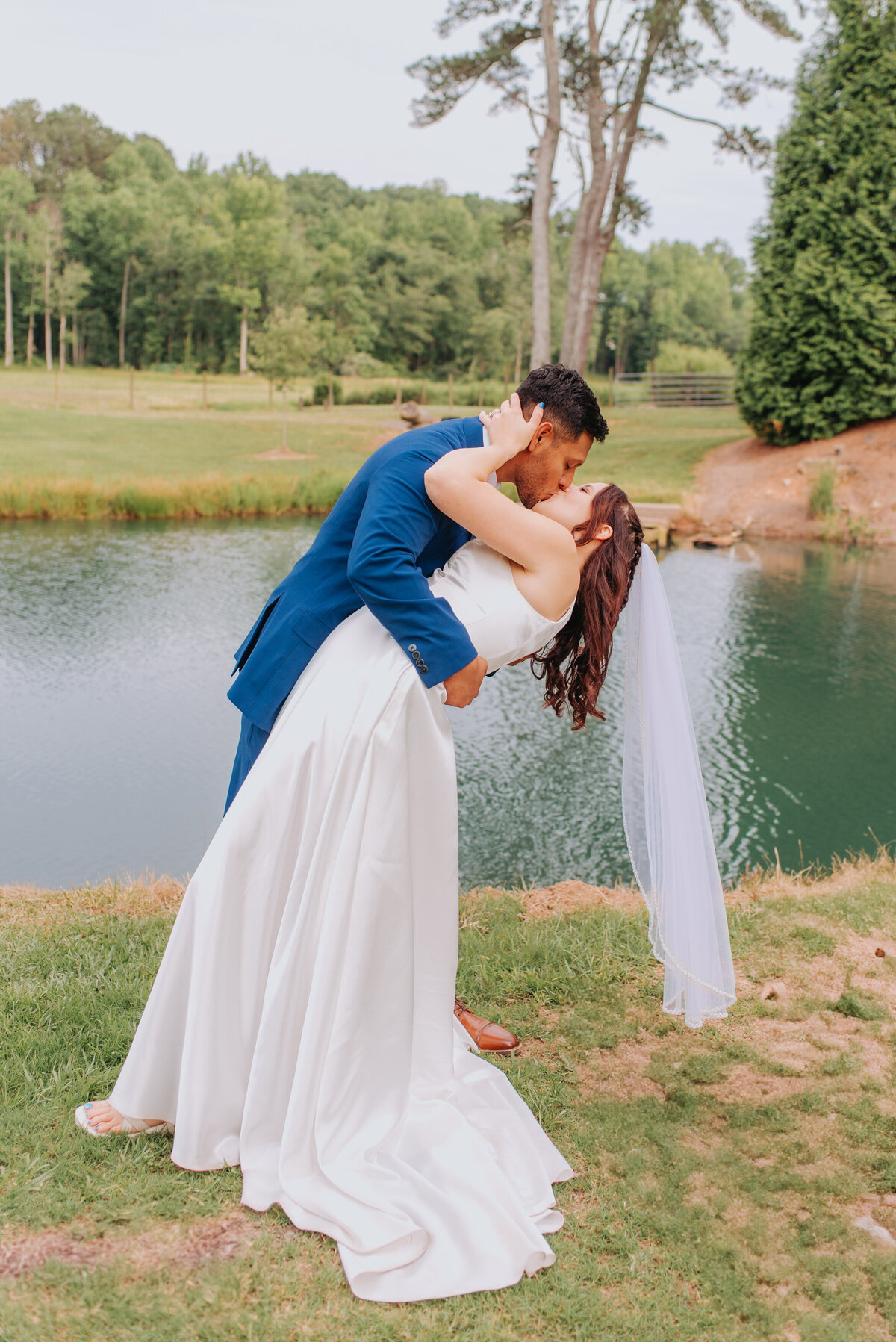 A couple kisses in front of a lake