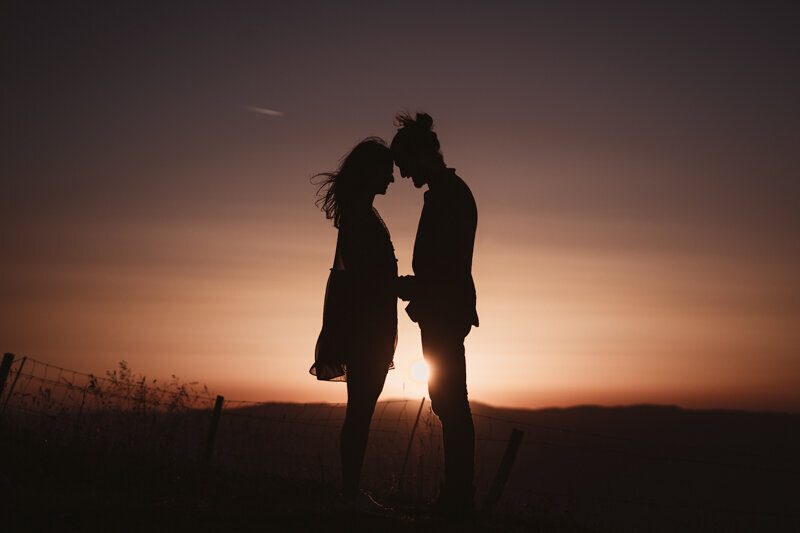 Contre-jour poétique d’un couple au coucher du soleil en Haute-Savoie, sur les hauteurs près d’Annecy.