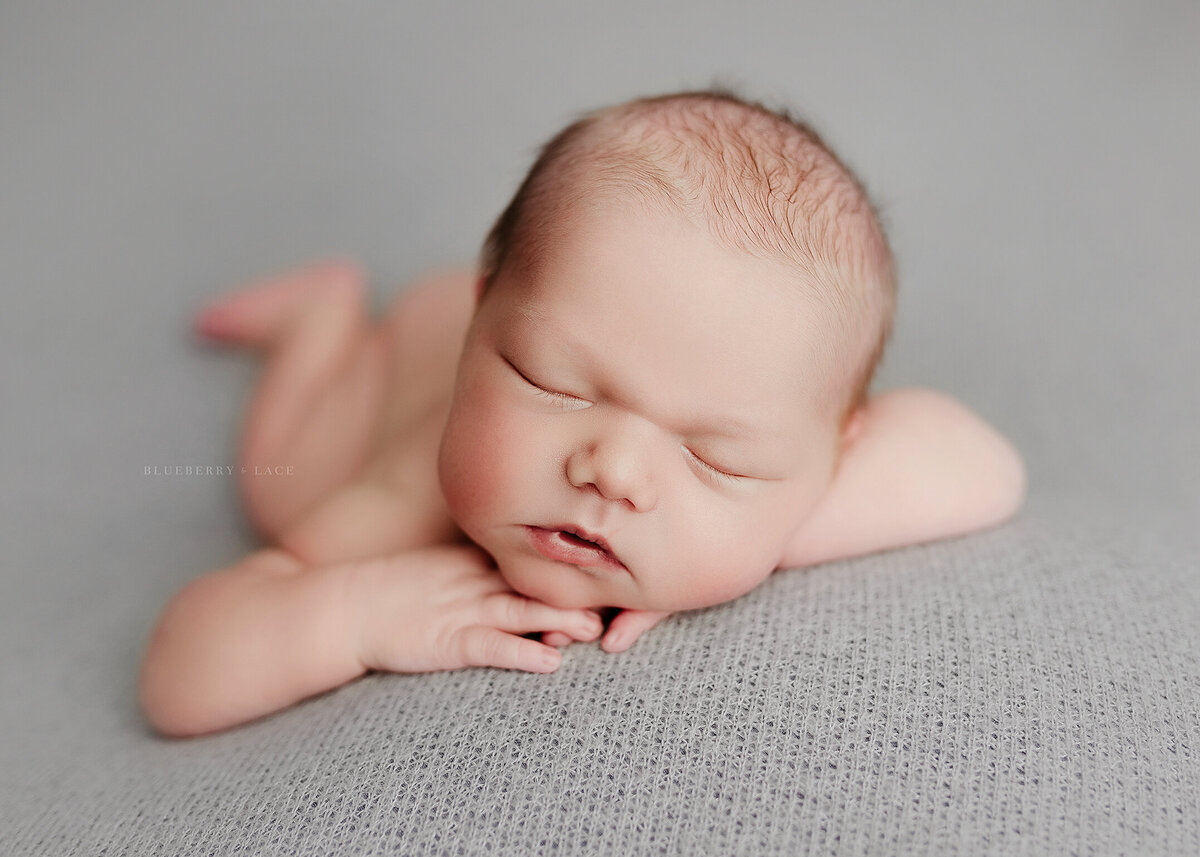 newborn baby boy laying on grey fabric naked for timeless photos
