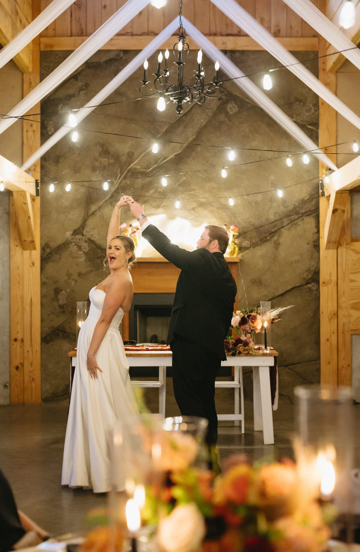 first dance between bride and groom in a Charlottesville wedding venues reception hall with groom twirling his bride under fairy lights