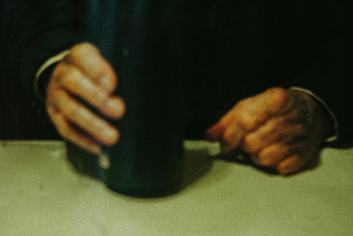 Film Photograph of an elderly man's hands holding his last bottle of homemade cider, part of The Quiet Gift series by Marie Kenny.