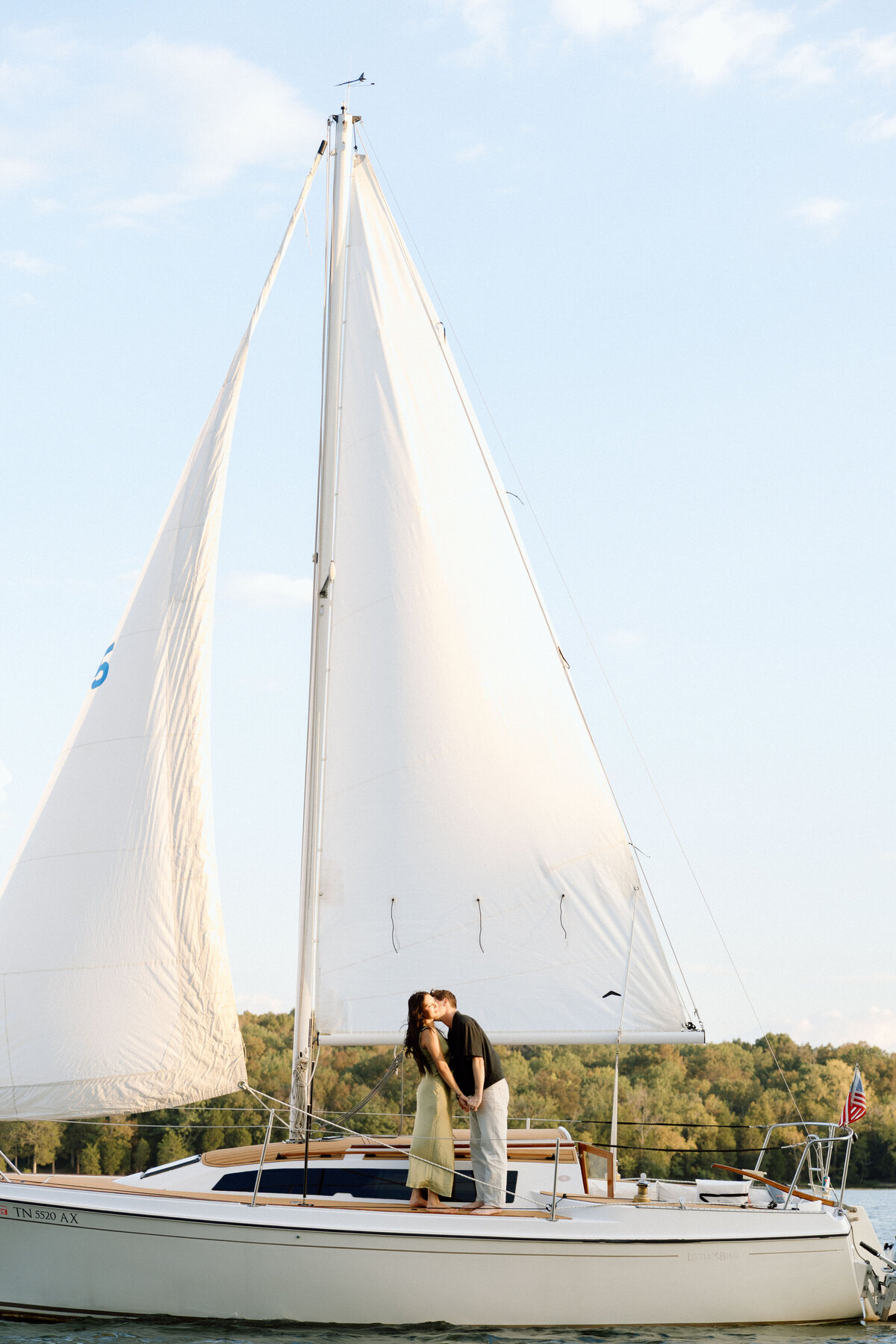 couple sharing a sweet moment on a sailboat during a sunset engagement session in nashville