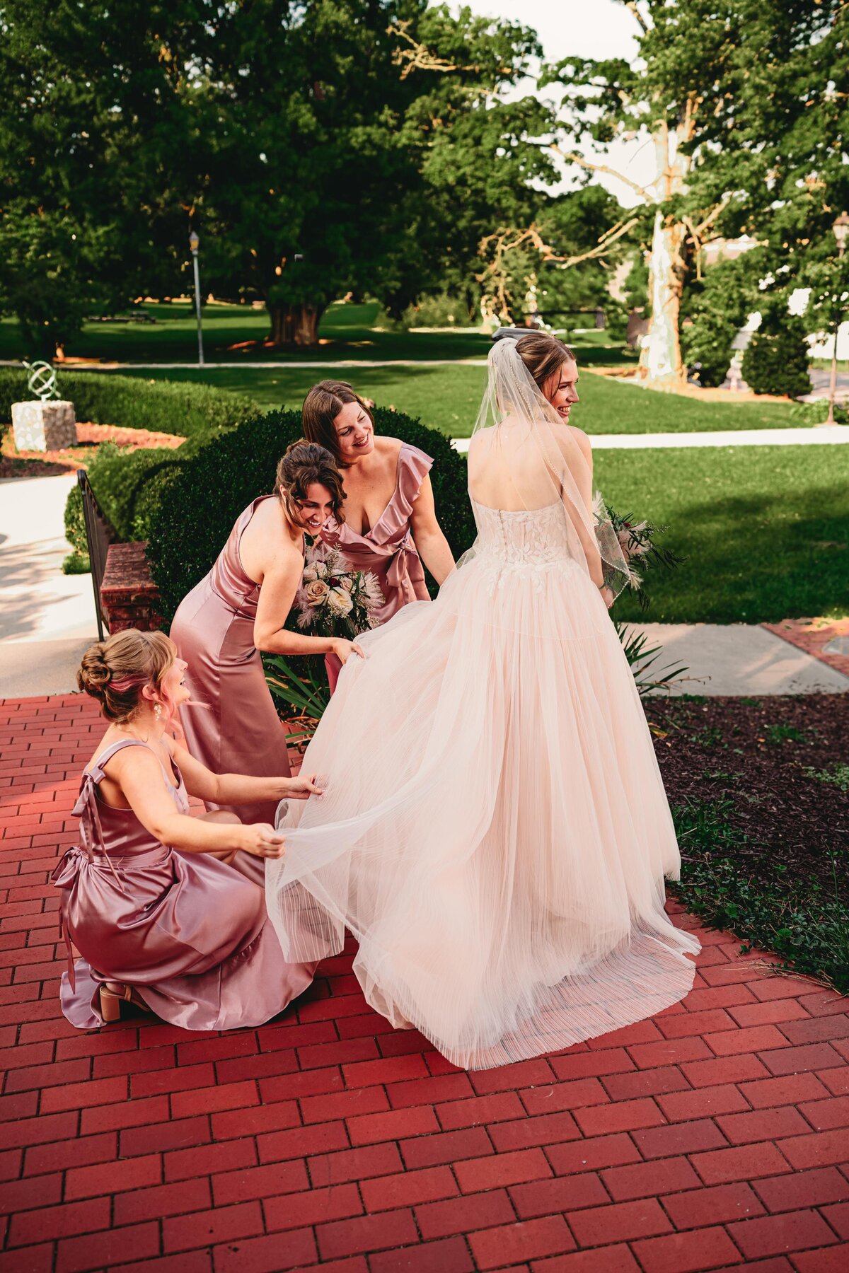 A bride surrounded by bridesmaids adjusting her dress before the ceremony, captured in a moody & editorial wedding photography style in Pittsburgh.