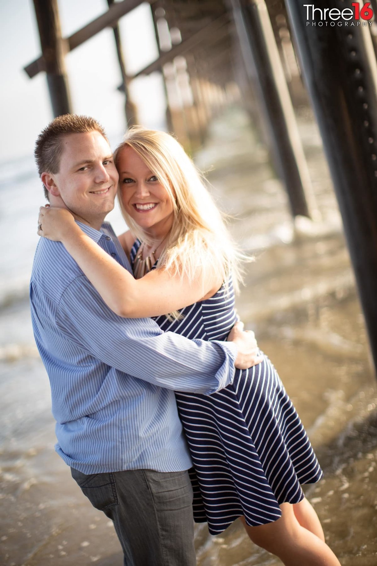Engaged couple embrace one another during their engagement photo shoot