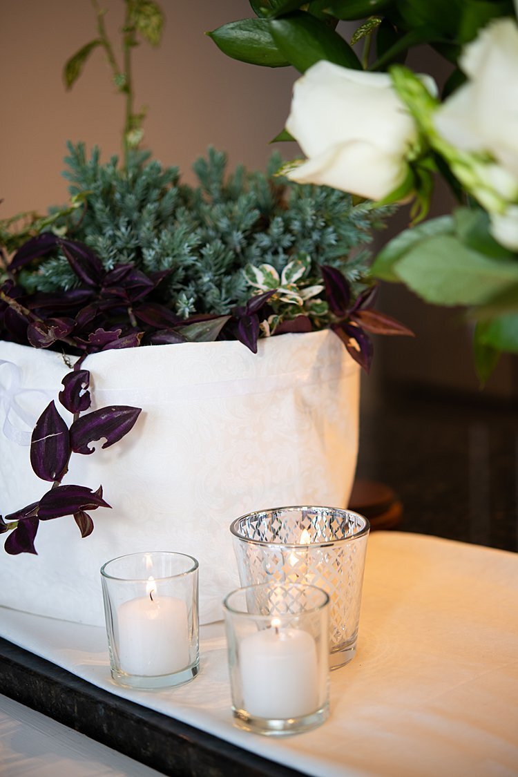 White votives and greenery at a wedding ceremony