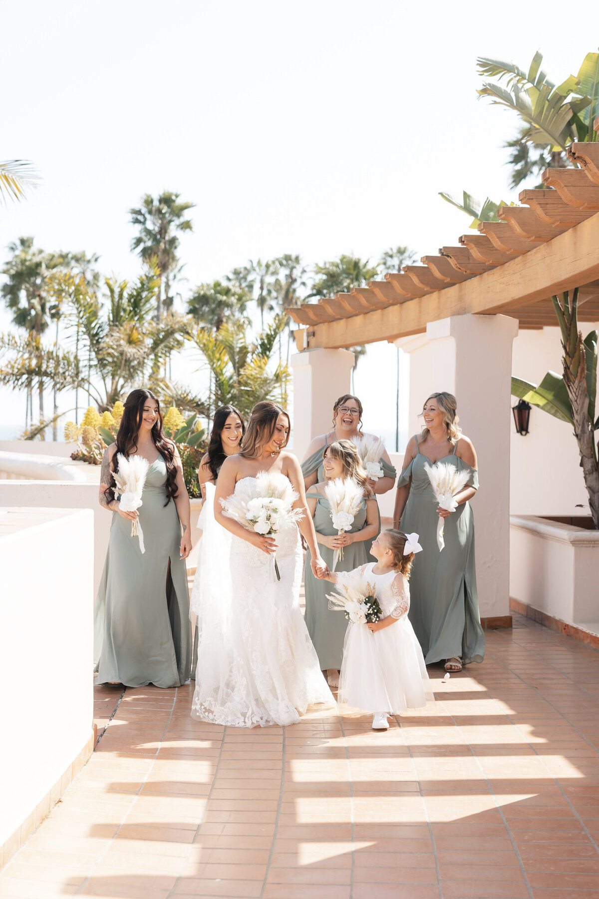 Bride and bridesmaids walking and looking at each other at Hilton Beachfront Resort Santa Barbara