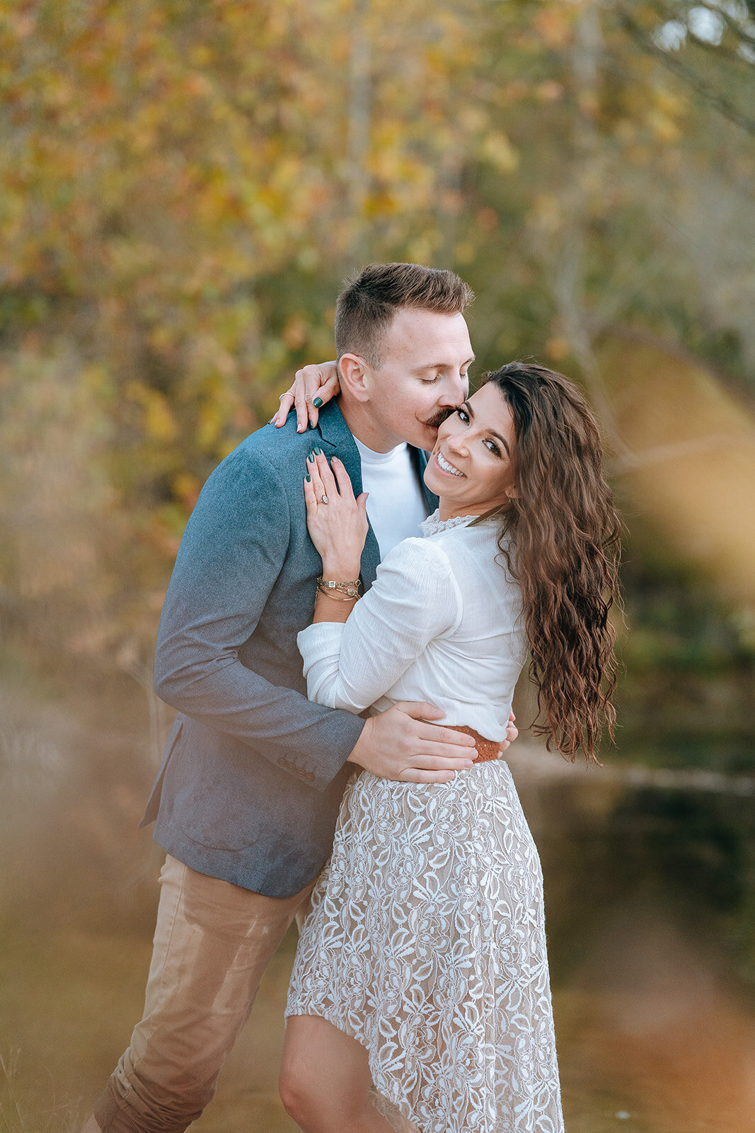 couple standing in lake embracing and smiling