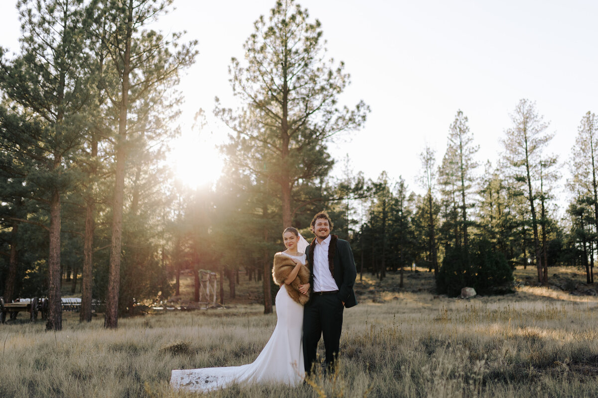 bride and groom smiling in field at golden hour in winter in flagstaff arizona